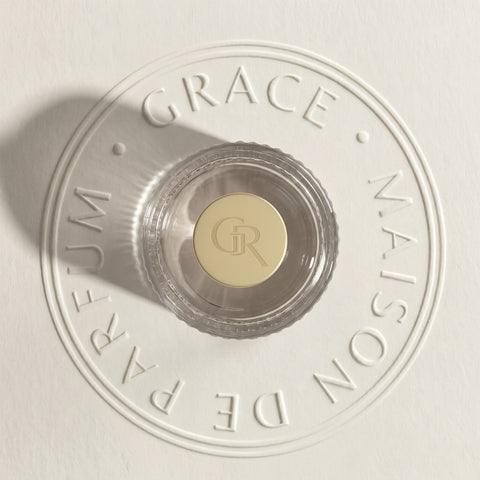 Close-up of a perfume bottle cap with 'Grace Maison de Parfum' branding on a light background.